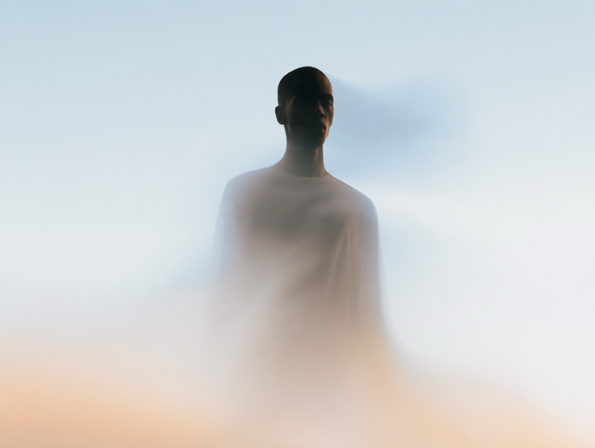 A man alone in fog, in peach and blue-grey light